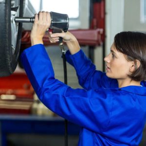 A capable female technician is depicted skillfully fixing a car wheel in a well-equipped workshop. The photo highlights the program's comprehensive education in automotive technology and management. Students are equipped with advanced skills to lead and excel in the dynamic automotive industry, ensuring the highest standards of vehicle maintenance and performance.