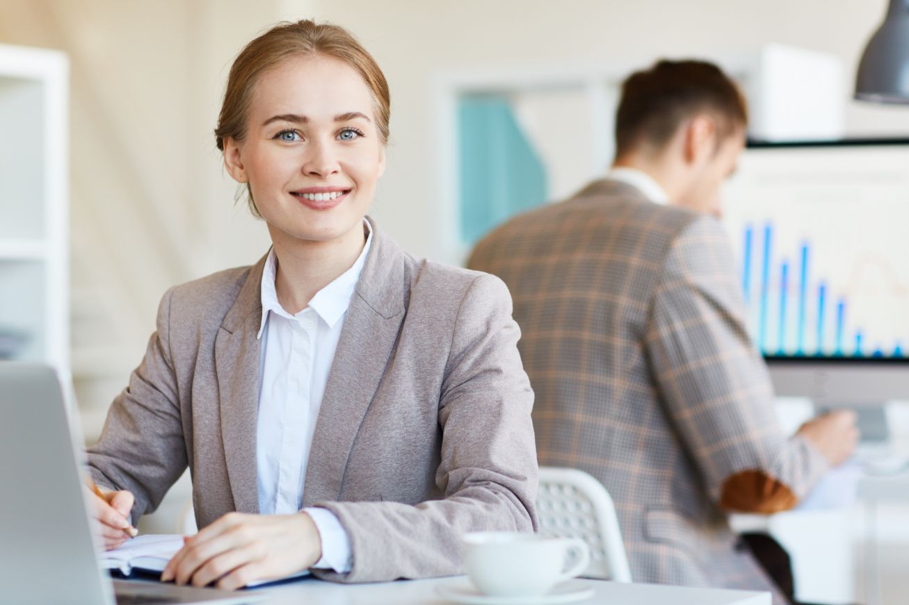 A professional businesswoman sits at her well-organized desk, surrounded by modern office equipment and resources. She confidently holds a pen, ready to tackle the challenges of the corporate world. The sleek and professional setting reflects the professional environment fostered at Sheffield College's business, leadership, and management courses, where students are equipped with the skills and knowledge needed for success