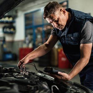 An experienced technician in a workshop is shown working on automotive electrical systems with precision. Wires, connectors, and electronic components are carefully attended to, emphasizing the technical expertise gained through the Certificate III in Automotive Electrical Technology at Sheffield College. This program equips students with the skills needed to excel in automotive electrical diagnostics and repairs.