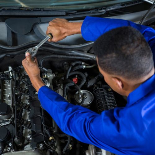 A mechanic focused on fixing a car, symbolizing the expertise gained in our Pack 2 program