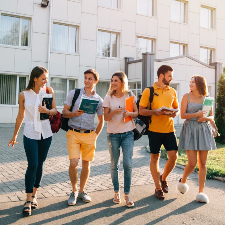 Joyful domestic students walking and smiling on campus.